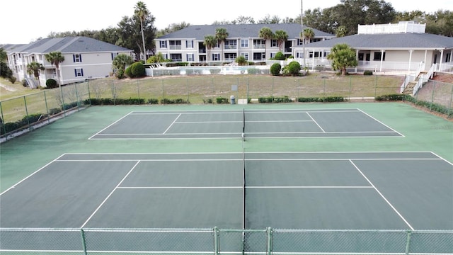 view of tennis court featuring a residential view and fence