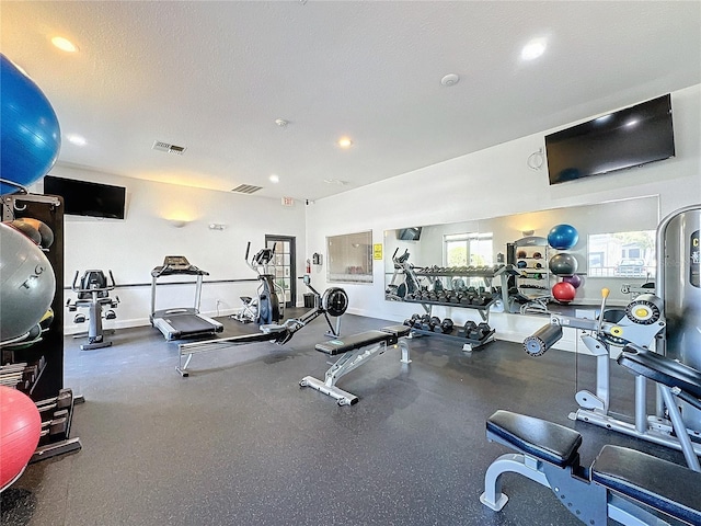 workout area featuring baseboards, visible vents, and a textured ceiling