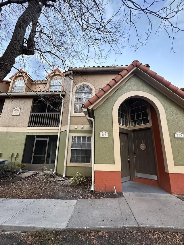 view of front of property featuring a balcony, a tile roof, and stucco siding