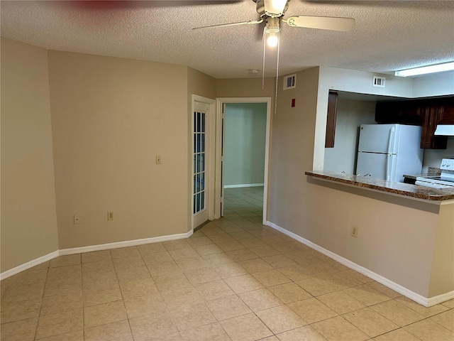 empty room with a ceiling fan, a textured ceiling, and baseboards