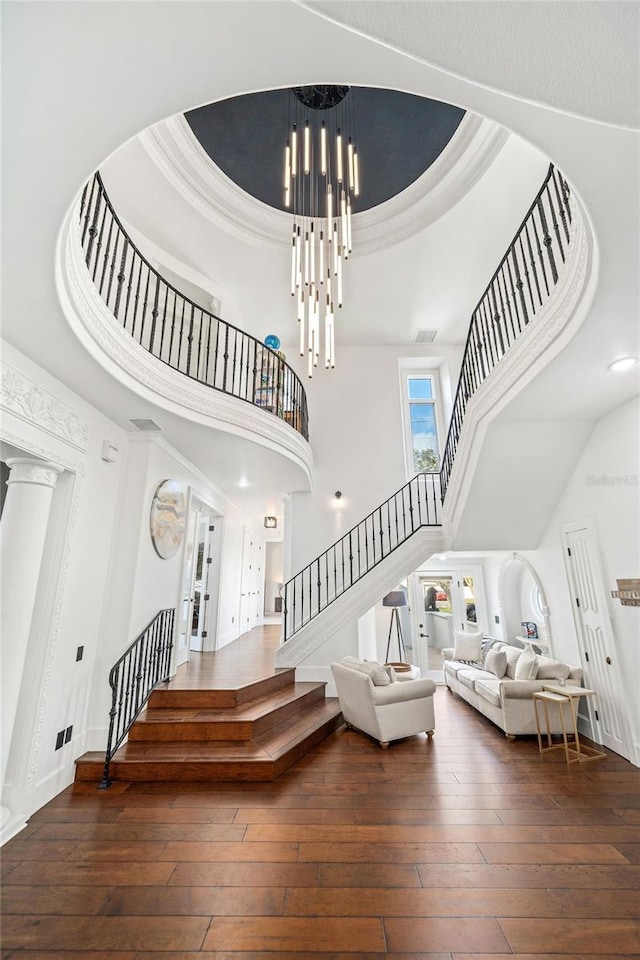 interior space with stairway, a tray ceiling, a towering ceiling, wood-type flooring, and a chandelier