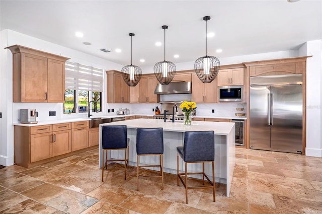 kitchen featuring stone tile floors, wine cooler, exhaust hood, light countertops, and built in appliances