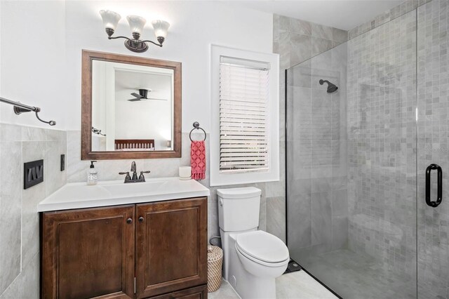 bathroom with vanity, tile walls, toilet, and a shower stall