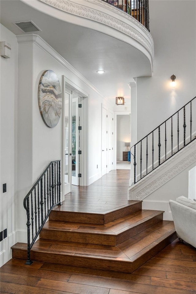 staircase featuring visible vents, crown molding, and hardwood / wood-style flooring