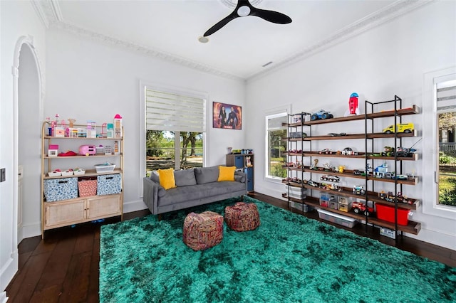 living area featuring dark wood-style floors, baseboards, ornamental molding, and a ceiling fan