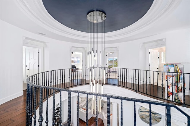 hallway with visible vents, an upstairs landing, ornamental molding, hardwood / wood-style flooring, and a raised ceiling