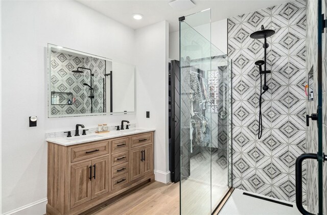 bathroom with a shower stall, wood finished floors, double vanity, and a sink