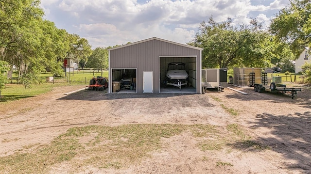 detached garage featuring fence and dirt driveway