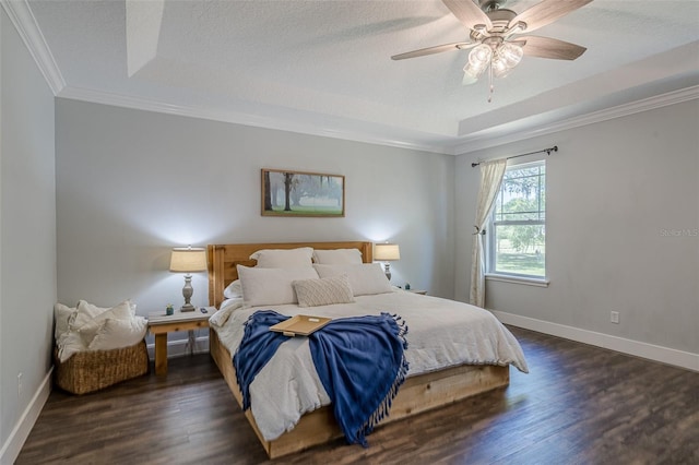 bedroom with a tray ceiling, a textured ceiling, dark wood-style floors, crown molding, and baseboards