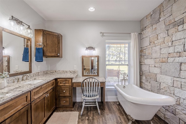 bathroom featuring a soaking tub, vanity, and wood finished floors