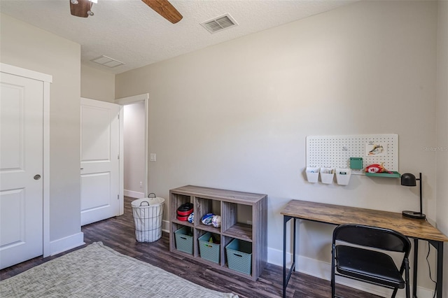 interior space with a ceiling fan, baseboards, wood finished floors, visible vents, and a textured ceiling