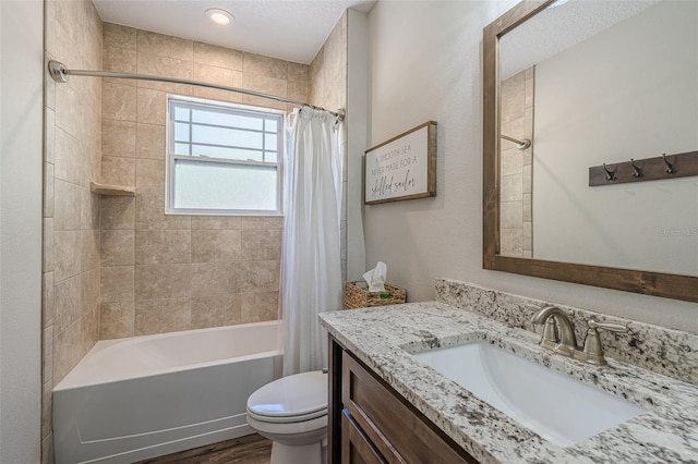 bathroom with toilet, vanity, wood finished floors, shower / bath combination with curtain, and a textured ceiling