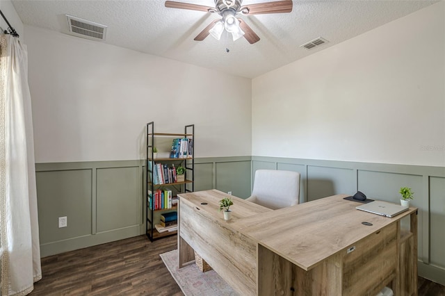 office space with a textured ceiling, wainscoting, visible vents, and ceiling fan