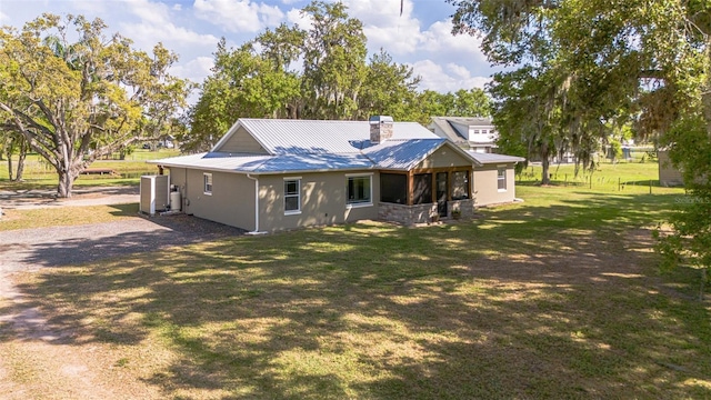 rear view of house with a yard, metal roof, and a chimney