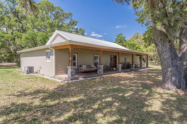 rear view of house featuring a patio, a yard, central AC unit, and stucco siding