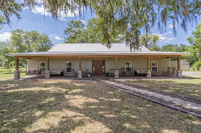 rear view of property with a lawn, metal roof, and outdoor lounge area