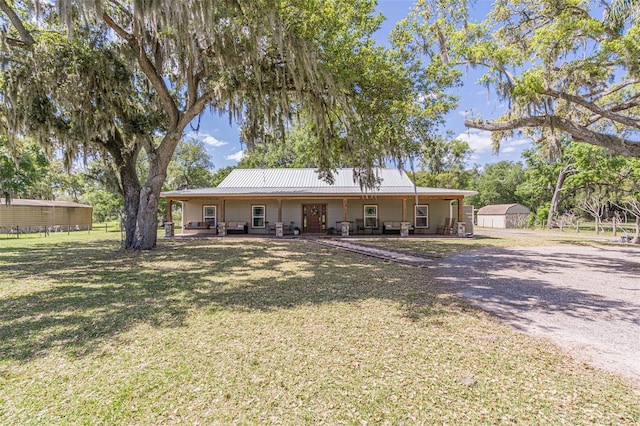 rear view of house with a porch, metal roof, and a yard