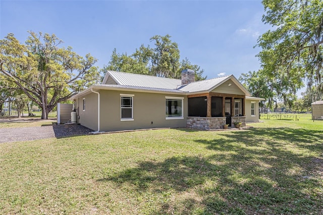 back of property featuring stucco siding, a yard, a chimney, and metal roof