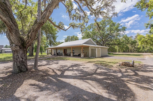 back of house featuring metal roof, covered porch, and driveway