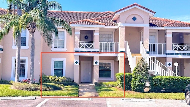 view of front of home with stucco siding, a tiled roof, and uncovered parking