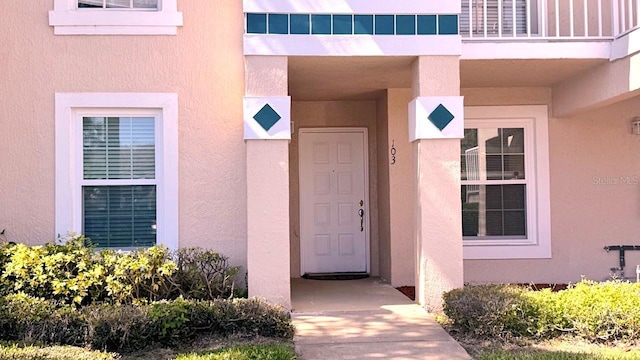 doorway to property with a balcony and stucco siding