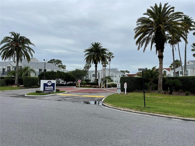 view of street featuring traffic signs, a residential view, curbs, and street lighting