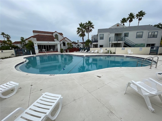 community pool with a patio and fence