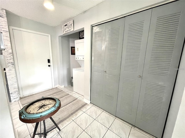 2560 Woodgate Blvd Unit 203, Orlando, FL 32822 - foyer entrance featuring stacked washer / dryer, a textured ceiling, and baseboards