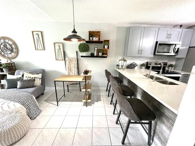 2560 Woodgate Blvd Unit 203, Orlando, FL 32822 - kitchen featuring appliances with stainless steel finishes, a textured ceiling, light countertops, gray cabinets, and a breakfast bar area