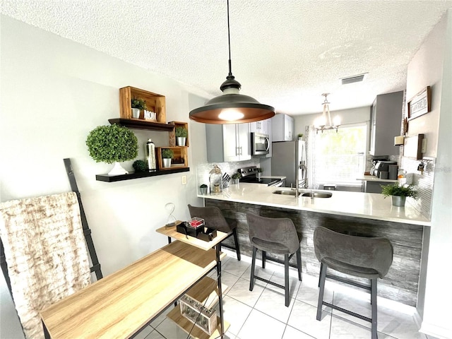 2560 Woodgate Blvd Unit 203, Orlando, FL 32822 - kitchen featuring stainless steel appliances, a kitchen bar, a sink, light tile patterned flooring, and light countertops