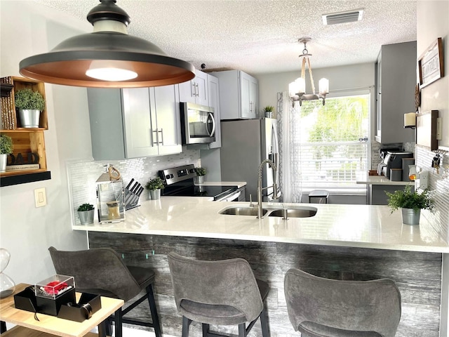 2560 Woodgate Blvd Unit 203, Orlando, FL 32822 - kitchen featuring stainless steel appliances, a sink, decorative backsplash, a peninsula, and a textured ceiling