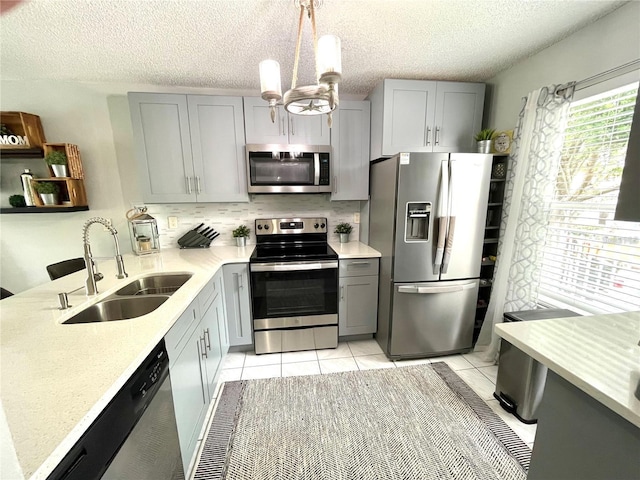 2560 Woodgate Blvd Unit 203, Orlando, FL 32822 - kitchen featuring stainless steel appliances, a sink, gray cabinetry, backsplash, and pendant lighting