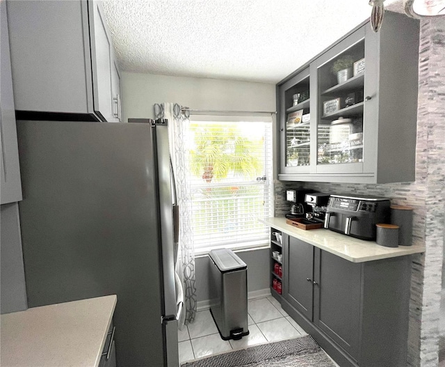 2560 Woodgate Blvd Unit 203, Orlando, FL 32822 - kitchen featuring freestanding refrigerator, light tile patterned floors, light countertops, gray cabinets, and glass insert cabinets