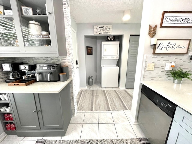 2560 Woodgate Blvd Unit 203, Orlando, FL 32822 - kitchen featuring stacked washer and clothes dryer, dishwasher, tasteful backsplash, gray cabinetry, and a textured ceiling