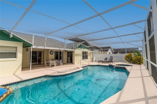 view of swimming pool featuring a pool with connected hot tub, a patio, and glass enclosure