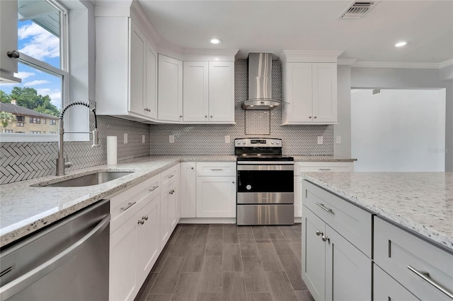 415 S 9th St, Leesburg, FL 34748 - kitchen with decorative backsplash, white cabinets, wall chimney exhaust hood, appliances with stainless steel finishes, and a sink