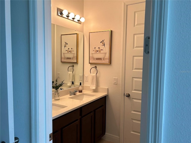 bathroom with double vanity, baseboards, and a sink