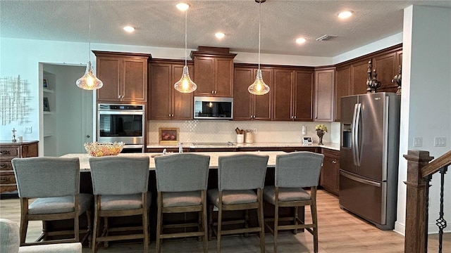 kitchen featuring dark brown cabinetry, visible vents, stainless steel appliances, and light countertops