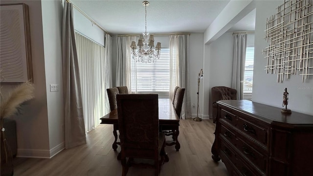 dining space with a wealth of natural light, a notable chandelier, a textured ceiling, and light wood finished floors