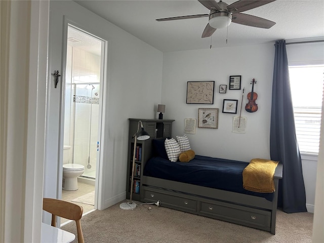 bedroom with a ceiling fan, light colored carpet, and connected bathroom