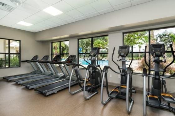 exercise room with a healthy amount of sunlight, visible vents, and a paneled ceiling