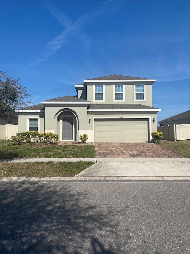 traditional-style house with stucco siding, an attached garage, and decorative driveway