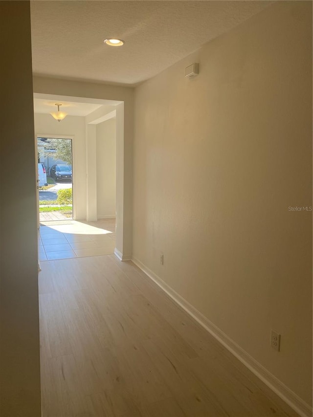 spare room with recessed lighting, baseboards, a textured ceiling, and wood finished floors