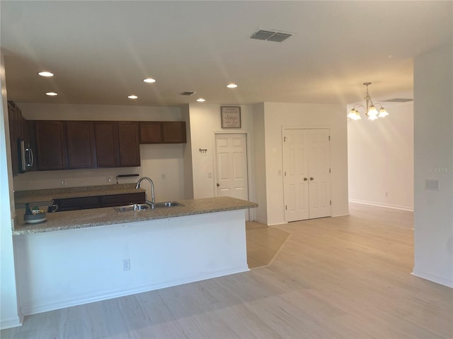 kitchen featuring a sink, stainless steel microwave, recessed lighting, a peninsula, and dark brown cabinets