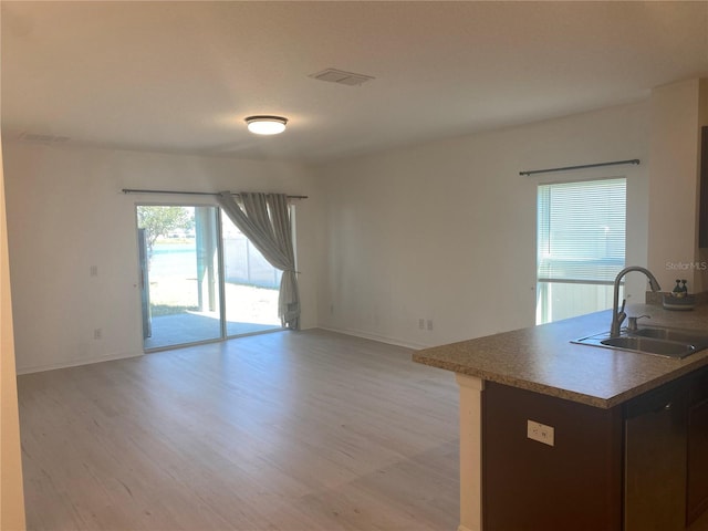 kitchen with visible vents, light wood-style flooring, open floor plan, and a sink