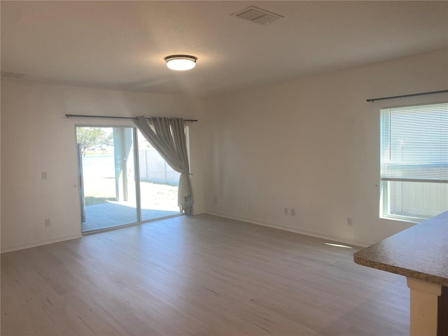 unfurnished room featuring visible vents, baseboards, and light wood-style floors