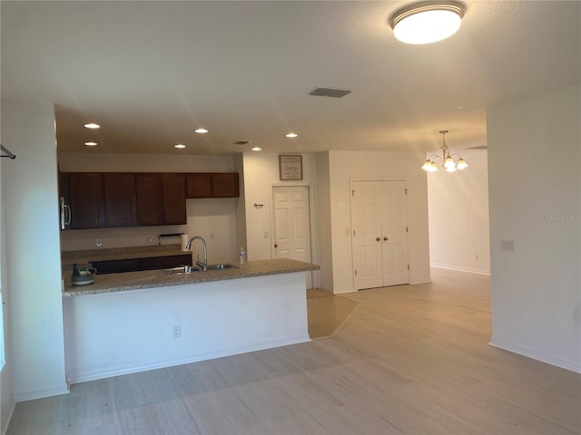 kitchen with visible vents, light stone counters, recessed lighting, a peninsula, and a sink