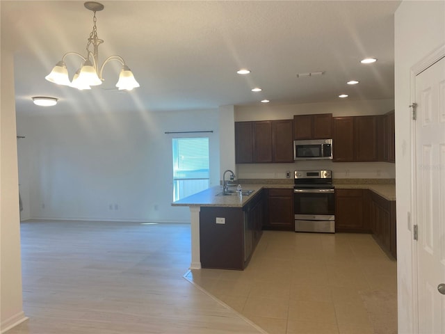 kitchen featuring visible vents, a peninsula, a sink, appliances with stainless steel finishes, and pendant lighting