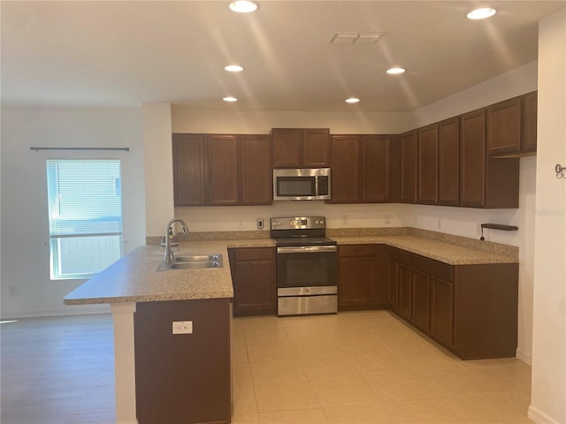 kitchen with light countertops, recessed lighting, appliances with stainless steel finishes, a peninsula, and a sink