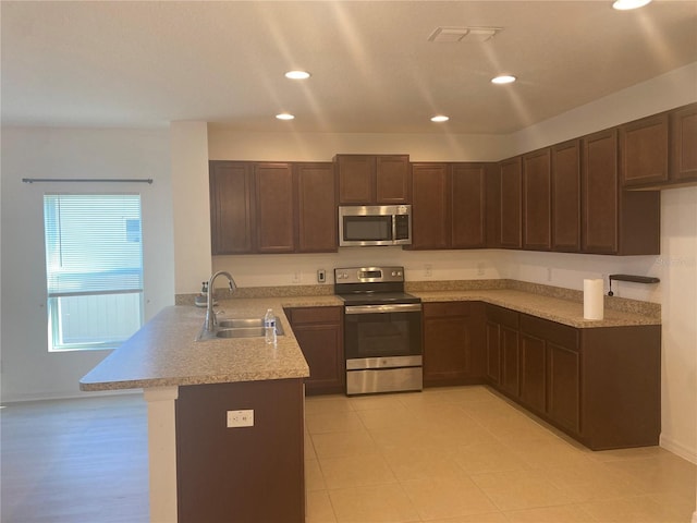 kitchen featuring visible vents, a peninsula, a sink, light countertops, and appliances with stainless steel finishes